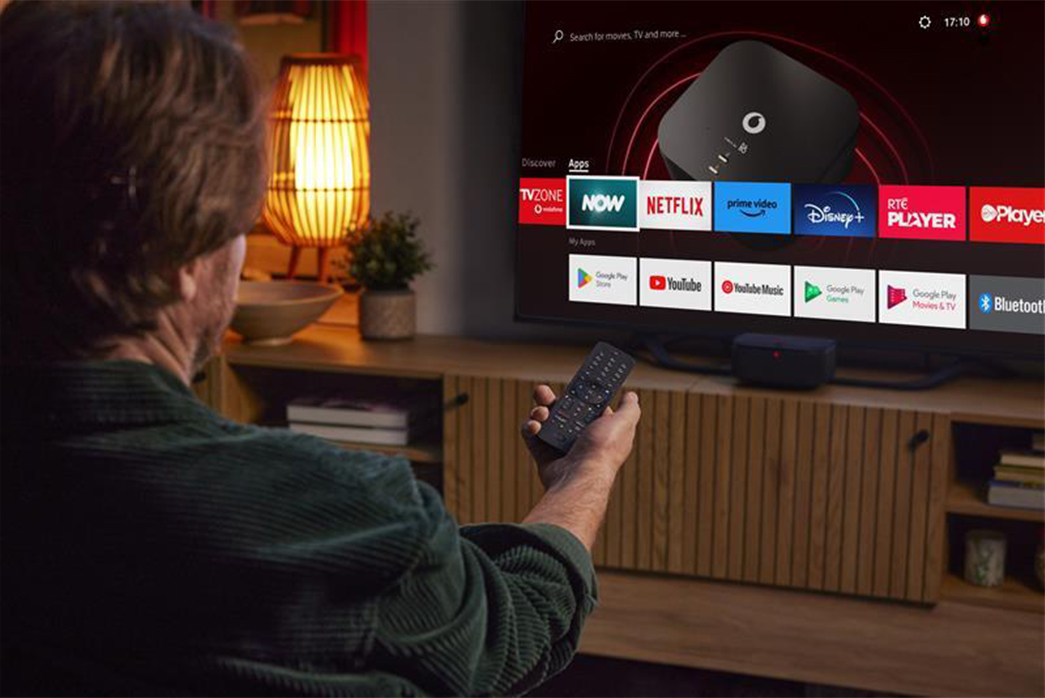 A man holds a remote control, poised in front of a smart television.